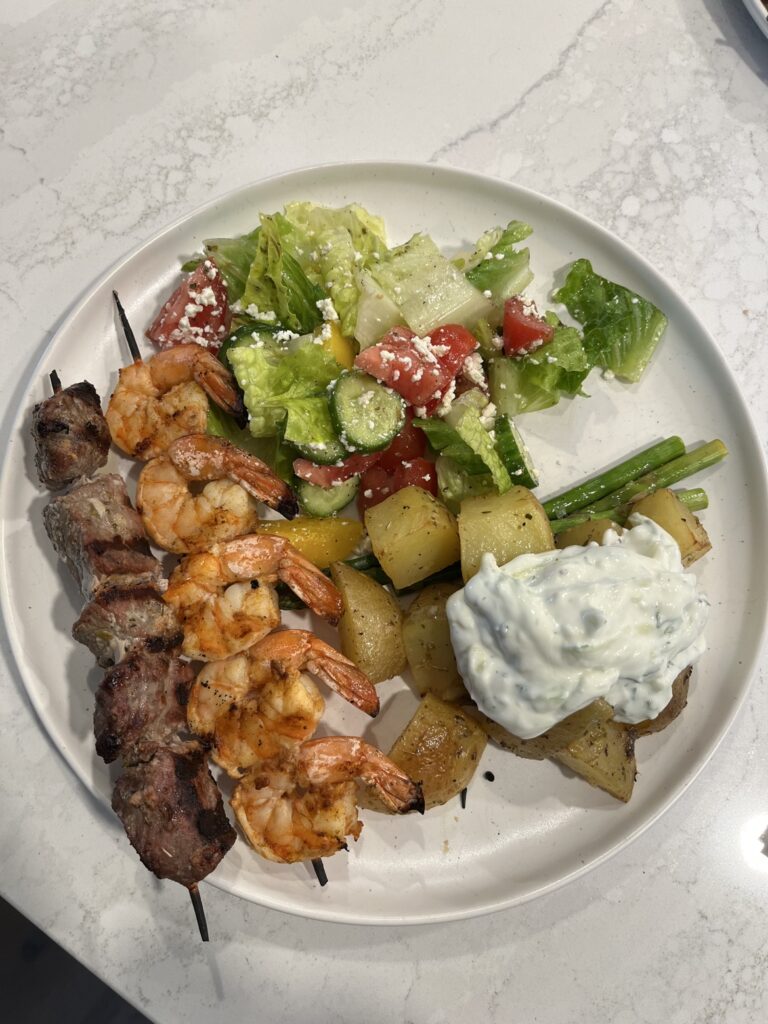 Homemade Greek feast with souvlaki skewers, Greek salad, lemon potatoes and tzatziki